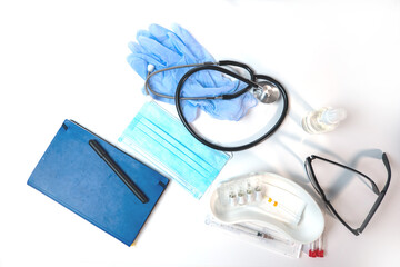 medical supplies, glasses, gloves, surgical mask, syringes and ampoules on a white table