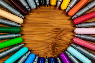 AN OCD pattern of markers arranged in a circle on a wood table.  Room for copy in the center