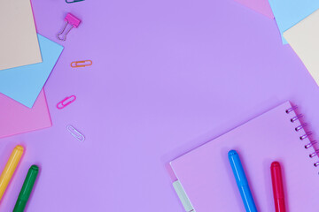 School desk with colorful stationery on purple background.