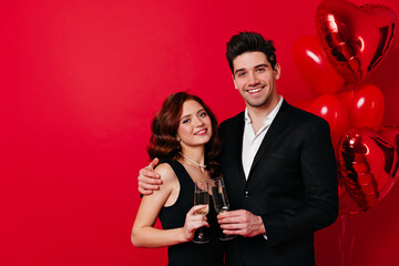 Good-humoured couple enjoying valentine's day. Man embracing girlfriend and drinking champagne.