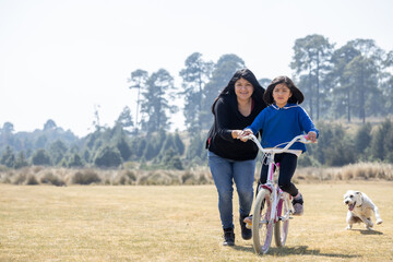 Fototapeta premium mexican mother teaching her daughter to ride a bicycle