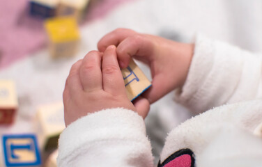 Aprendizaje infantil. Un bebé jugando con una pieza de madera educativa en sus manos.