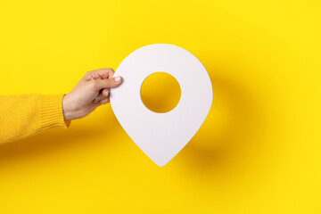 3D location symbol in hand over yellow background