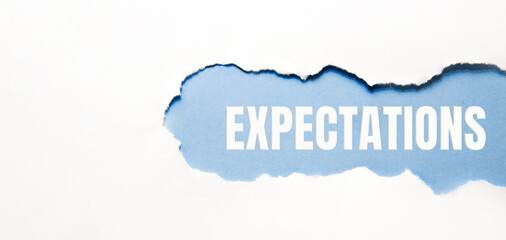 inscription Expectations word on blue torn papper