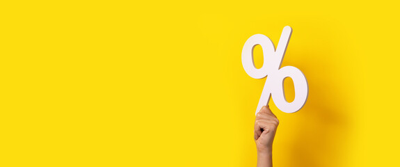 percentage sign in hand over yellow background, panoramic mock-up
