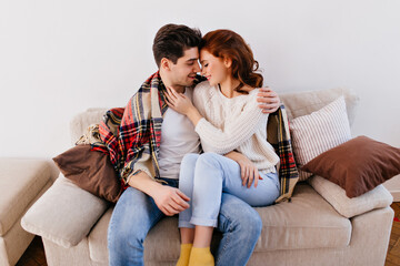 Glad young man embracing girlfriend. Indoor shot of couple enjoying domestic life.