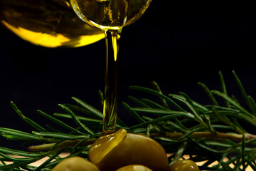 Glass bottle with virgin olive oil on a table with olives. Selective focus