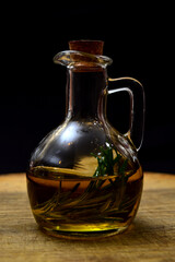 Glass bottle with virgin olive oil on a table with olives. Selective focus
