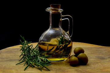 Glass bottle with virgin olive oil on a table with olives. Selective focus
