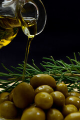 Glass bottle with virgin olive oil on a table with olives. Selective focus