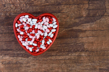 Obraz na płótnie Canvas Candy coated sunflower seeds, red, pink, and white, in a heart shaped ceramic dish, Happy Valentines Day 