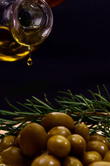 Glass bottle with virgin olive oil on a table with olives. Selective focus