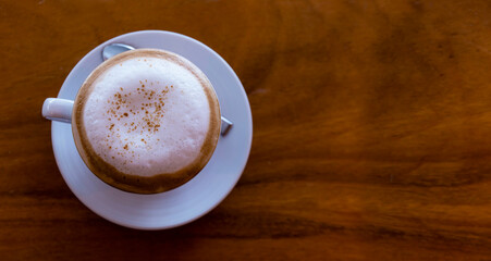Top view close up of hot espresso coffee in a white ceramic cup on a wood table background.