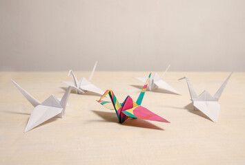 Paper crane birds four made out of white paper and one in the middle colorful , representing...