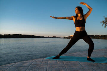 Young woman in Tai Chi pose, outdoors in by the river, energy balance and vitality 