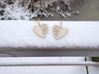 Two wooden carved hearts in the snow, selective focus, copy space
