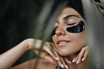 Selective focus of wonderful lady with eye patches. Graceful girl doing face treatment on nature background.