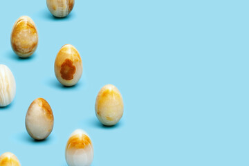 Pattern from Easter eggs from Natural gemstone onyx on blue paper. Trendy spring holiday arrangement.