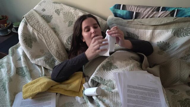 Sick student girl wipes her nose with toilet paper on the bed, top view
