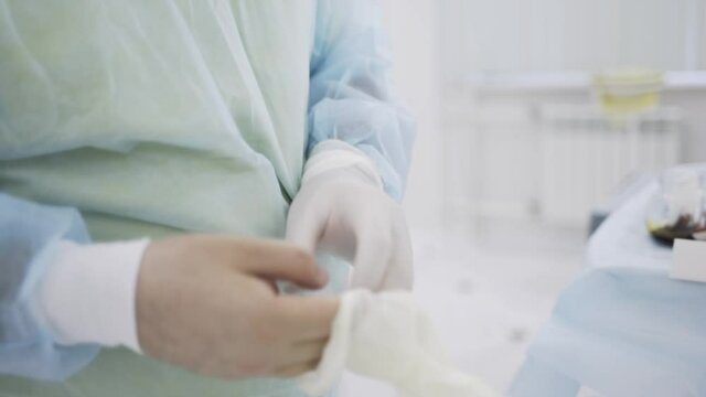 Close up of a nurse taking a sterile glove in the hospital. Action. Preparation for the surgery in the operating room, concept of medicine.
