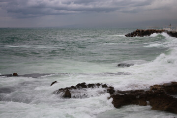 Fototapeta na wymiar Mediterranean Sea waves washing over rocks on the shore in Beirut, Lebanon, in stormy weather