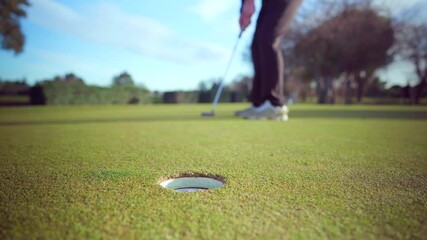 Succesful putting shot by golfer on the putting-green of a golf course on a sunny day, close-up on the hole - Powered by Adobe