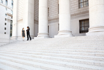 Two women in discussion on the exterior steps of a courthouse. Could be lawyers, business people...