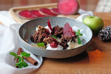 An unusual dessert in a plate of torn sponge cake, beetroot slices, nuts with apple and mint leaves