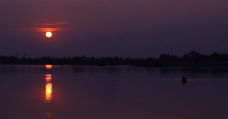 The scenery along the lake has an orange sky and a beautiful sunset.