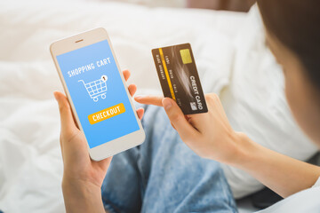 Young woman holding smartphone and online shopping with payment credit card on internet at home.