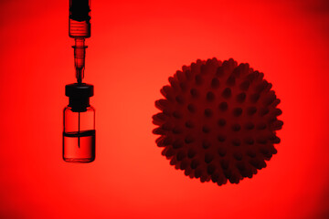 .The Coronavirus Vaccine and Syringe injection with a coronavirus infection, microbe on a red...