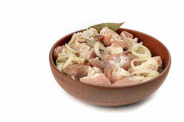 Boneless pork steak, sliced and marinated with onions, meat in a clay plate, white isolated background, close-up.
