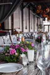 Modern veranda restaurant interior, flowers, banquet setting, glasses, plates