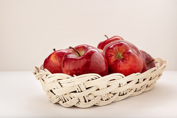 Apples red-yellow, juicy in a wicker basket on a light background