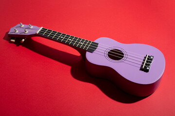 Four string ukulele guitar on red background