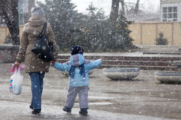 Obraz premium Mom and baby on the street during a snowfall