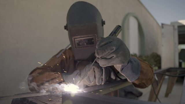 Person with protection mask is welding a metal object, sparks shooting