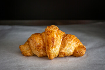 Croissants on heat-resistant paper in the oven with a black background.