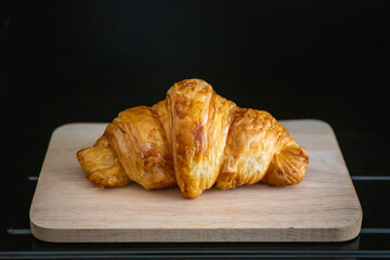 Croissant on a wooden plate on a black background