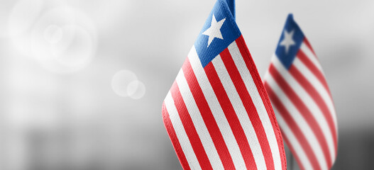 Small national flags of the Liberia on a light blurry background