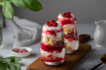 Trifles with raspberries and whipped cream in glass glasses.