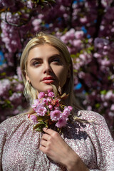 Fototapeta premium Spring girls fashion. Almond flowers blossoms. Beautiful young woman walking near the blossoming tree.