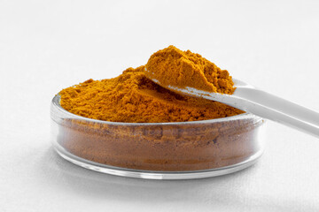 turmeric powder in a small glass container and a spoon