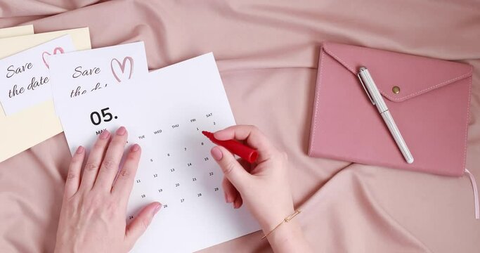 Woman hands putting save the date card in the envelope. Wedding planning, invitation concept. Top view