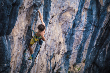 Fototapeta premium A strong man climbs a rock, Rock climbing in Turkey.