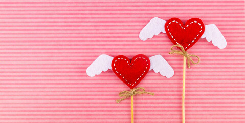 Valentine's Day background. Two hearts with handmade wings on a pink background.