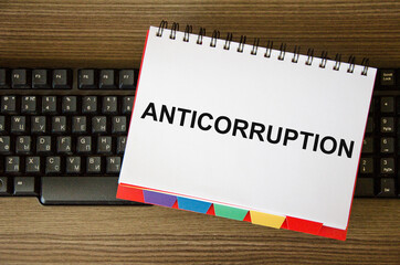 anticorruption text is written on a white notepad that lies on the computer keyboard