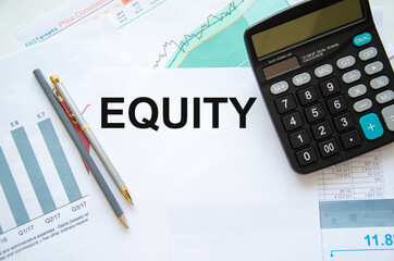word equity written on a white sheet of paper that lies on a financial chart near a calculator and...