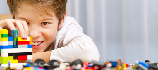 young boy playing with plastic construction toys at home.