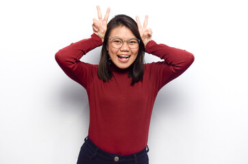 Finger on head as bunny ears of Young beautiful asian women dress red shirt isolated on white background